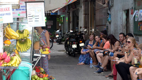 Một nhóm du khách ngồi hóng mát trong một con hẻm đường Bùi Viện - Ảnh: Quỳnh Trung