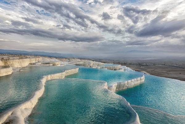 <strong>Pamukkale, Denizli, Thổ Nhĩ Kỳ: </strong>Pamukkale dịch ra có nghĩa là “Lâu đài bông”. Tên gọi này xuất phát từ màu trắng huyền ảo của những bờ đá hình thành do suối nước nóng ở miền Tây Nam Thổ Nhĩ Kỳ. Được coi là báu vật quốc gia, nơi này được bảo vệ chặt chẽ, nhưng du khách vẫn được phép xuống ngâm mình trong những hồ nước nhỏ và nông này. Ảnh: Ibellhop. <strong>Pamukkale, Denizli, Thổ Nhĩ Kỳ: </strong>Pamukkale dịch ra có nghĩa là “Lâu đài bông”. Tên gọi này xuất phát từ màu trắng huyền ảo của những bờ đá hình thành do suối nước nóng ở miền Tây Nam Thổ Nhĩ Kỳ. Được coi là báu vật quốc gia, nơi này được bảo vệ chặt chẽ, nhưng du khách vẫn được phép xuống ngâm mình trong những hồ nước nhỏ và nông này. Ảnh: Ibellhop.