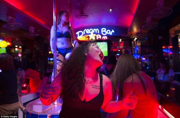 Một phụ nữ làm ở quán bar khá nổi tiếng nhảy theo điệu nhạc trong lúc đồng nghiệp của cô múa cột phía sau. 