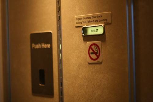 Nhà vệ sinh có thể mở từ bên ngoài: Nhà vệ sinh trên máy bay thường có khóa phụ giấu sau biển báo cấm hút thuốc. Bạn chỉ cần nhấc nó ra và đẩy chốt sang một bên để mở khóa. Ảnh: Nextshark.