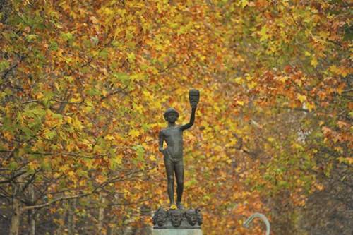 Bức tượng cậu bé bán mặt nạ nổi tiếng của Zacharie Astruc với nền lá thu trong vườn Luxembourg