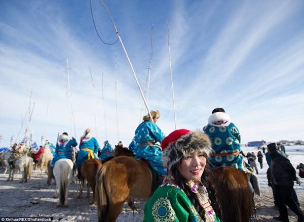 Nam nữ thanh niên trong trang phục truyền thống, đầu đội mũ lông diễu hành trên lưng lạc đà 2 bướu.