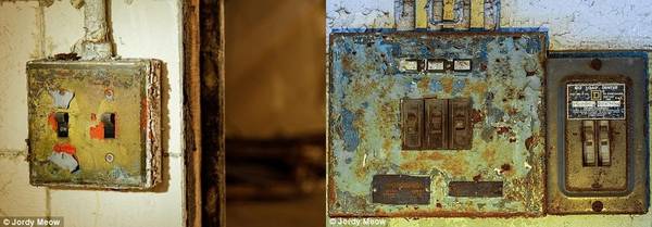 Những khung cửa vênh và công tắc đèn han gỉ được chụp lại bên trong tòa nhà bỏ hoang.