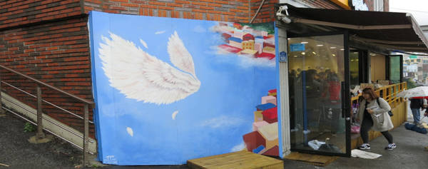 Hình đôi cánh thiên thần nổi tiếng, nằm bên cạnh một cửa hàng lưu niệm với nhiều đồ trang trí xinh xắn có thể làm quà.