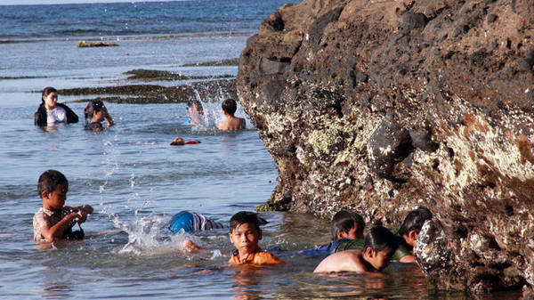  Những em nhỏ tắm biển và truy tìm trong đá núi những con ốc biển - Ảnh: Trần Mai