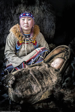 Một người mẹ dân tộc Evenki và con gái nhỏ của mình ở quận Neryungrinsky, Cộng hòa Sakha, Siberia. Người Evenki mặc quần áo phương Tây vào những tháng mùa hè, nhưng trong mùa đông lạnh, họ mặc trang phục truyền thống làm từ da báo và đeo trang sức đẹp bằng các loại hạt khác nhau tùy thuộc vào giới tính.