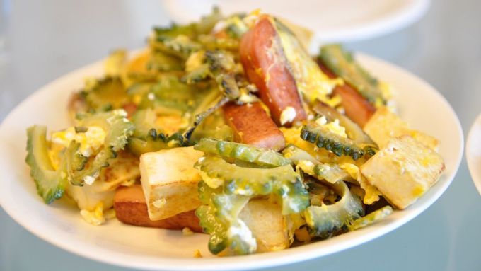 Goya champuru Nói đến ẩm thực Okinawa không thể không nhắc tới những món ăn nổi bật như goya champuru. Champuru, nghĩa là "trộn lẫn", một di sản ẩm thực của vùng. Món này gồm một số nguyên liệu, phổ biến nhất là có mướp đắng (goya), xào với đậu phụ, thịt heo và trứng. Món mướp này có thể làm theo nhiều cách, hoặc chiên như tempura hoặc thái mỏng và trộn trong salad hay với làm đồ muối để ăn kèm.