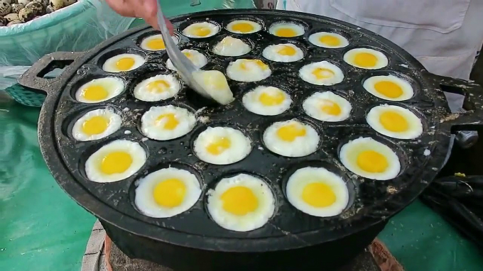 Trứng cút nướng được chế biến trong một khay lớn, có nhiều lỗ nhỏ giống như tổ ong. Món ăn nóng hổi, ăn không ngấy, du khách có thể tìm thấy ở nhiều quầy hàng trong các ngóc ngách ở chợ Chatuchak.