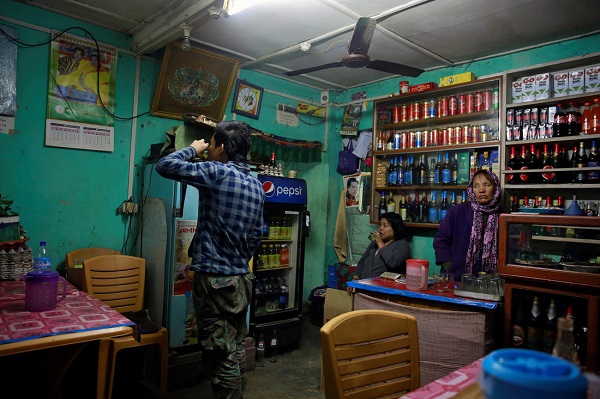 Một thanh niên đang uống cốc rượu bên trong một cửa hàng tạp hóa ở Thimphu.