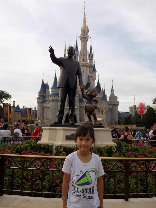 Một bé gái chụp ảnh trước tượng đài ông Walt Disney