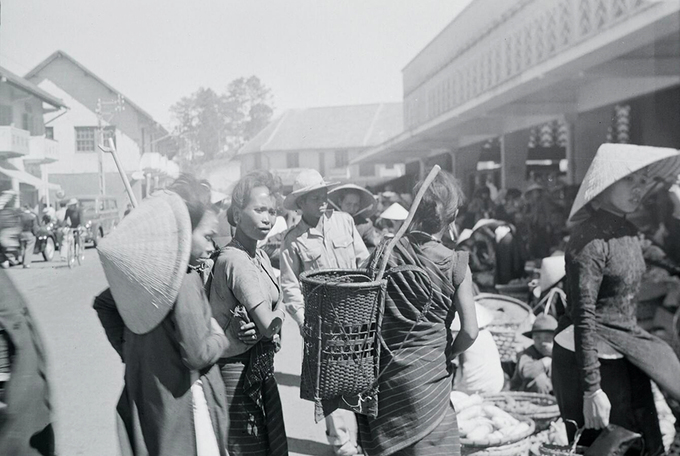 Khi mới đi vào hoạt động, chợ thường được dân địa phương gọi là "Chợ Cây" bởi các nguyên liệu sơ khai để xây dựng đều bằng gỗ. Trong hình là cảnh người dân đang mua bán được chụp năm 1956, trong đó có cả đồng bào dân tộc. Ảnh: Flickr.