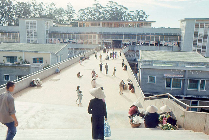 Đến năm 1958, một trong số hạng mục của khu chợ được xây dựng trên khu vực đầm lầy dưới sự chỉ đạo của kiến trúc sư Nguyễn Duy Đức. Cây cầu đi bộ nối thẳng tới Chợ Đà Lạt chụp trong khoảng năm 1965 - 1966. Ảnh: Flickr.