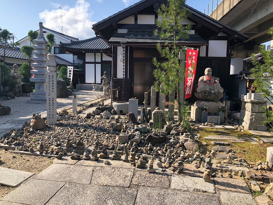 Một ngôi đền nhỏ trên đường đi xếp nhiều chồng đá trước cửa.