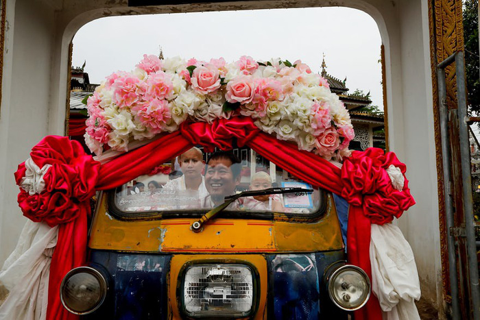 Một ông bố vui vẻ chở con trai mình trên chiếc xe trang trí đầy hoa đẹp. Ảnh: Jorge Silva/Reuters
