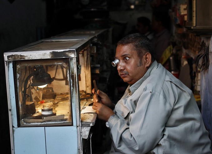 Trong con hẻm nhỏ ở khu phố cổ Delhi, một người đàn ông đang đeo kính lúp để sửa đồng hồ đeo tay. Trong thời đại kỹ thuật số, những người thợ dày dặn kinh nghiệm đang dần lạc hậu với công nghệ và những cửa tiệm nhỏ như của ông đã lỗi thời.  Ảnh: Anindito Mukherjee