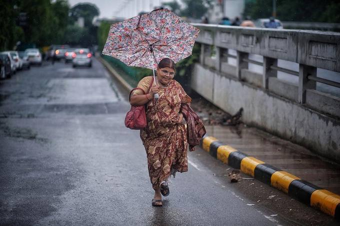 Một người phụ nữ đang chạy giữa cơn mưa để kịp bắt xe buýt. Ở một nơi đông đúc và thường xuyên ùn tắc giao thông như ở Delhi, người dân luôn phải chen chúc trên những chiếc xe buýt chật chội hàng ngày, theo The Hindu.