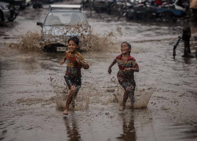 Những đứa trẻ chơi đùa trên đường phố ngập bùn lầy sau cơn mưa lớn.