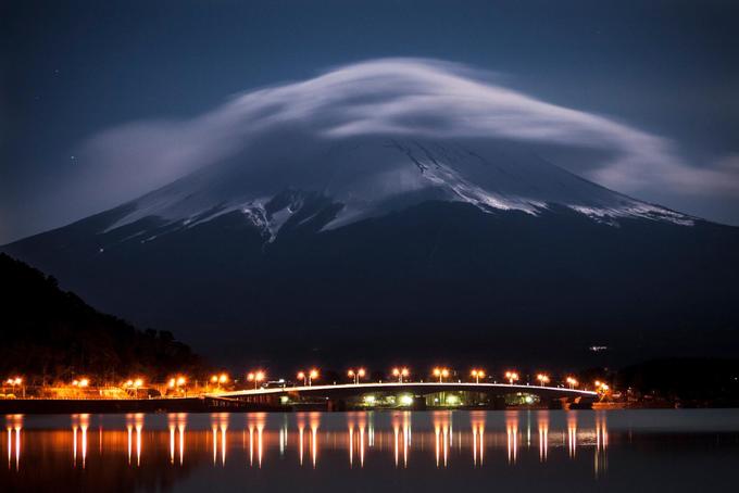 Núi Phú Sĩ phát sáng trong ánh trăng, bên dưới là hồ Kawaguchi được thắp sáng bằng đèn đường cao tốc vào lúc nửa đêm.