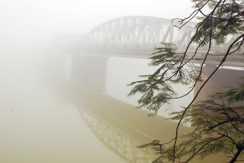 Cầu Trường Tiền nằm trên dòng sông Hương lúc mờ lúc tỏ giữa bốn bề mịt mù sương khói tỏa lên từ dưới lòng sông.