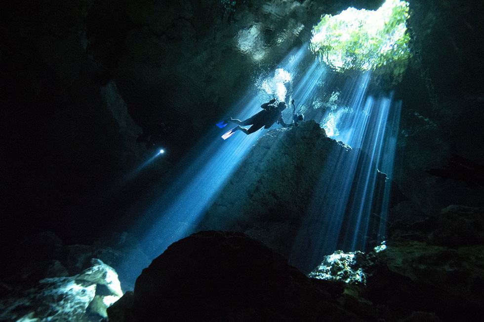 Một thợ lặn bơi dưới hang ngầm đang hướng về phía ánh nắng rọi xuyên qua bề mặt nước của hố sụt tự nhiên Taj Maha tại bang Quintana Roo - Ảnh: Donald Miralle/Getty/Lumix