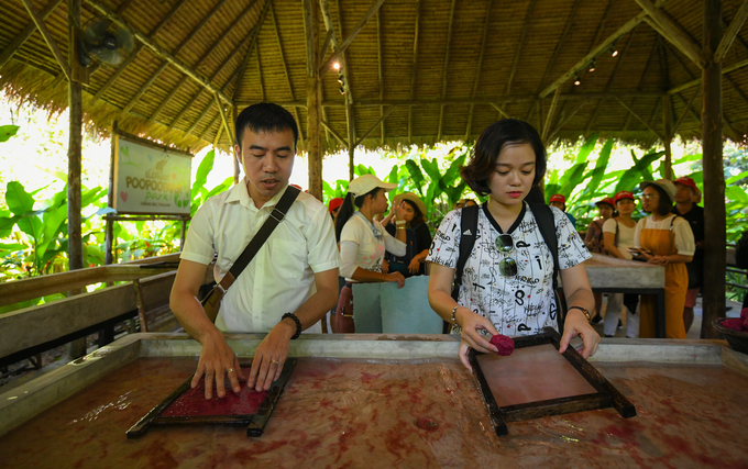 Anh Ngọc và chị My, hai du khách Việt Nam dàn bột giấy ra khung gỗ sau khi được Cee hướng dẫn cách làm. Theo anh Ngọc, dù vẫn hơi ghê nhưng anh vẫn muốn thử để có kỷ niệm khi nhớ đến Chiang Mai.