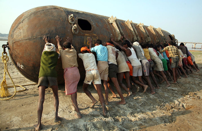 Người lao động cùng nhau di chuyển chiếc phao thép để xây cầu tạm trên sông Hằng. Ảnh: Jitendra Prakash/Reuters.