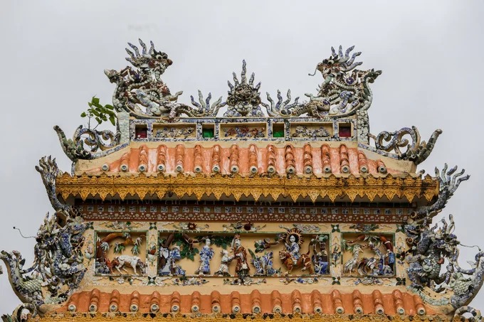 Trên tầng mái cổng tam quan được trang trí tinh xảo các tượng long, lân, quy, phượng, canh, mục, ngư tiều... Vật liệu bằng đồ sứ của Việt Nam, Trung Hoa với nước men xanh tạo nên màu sắc óng ánh.