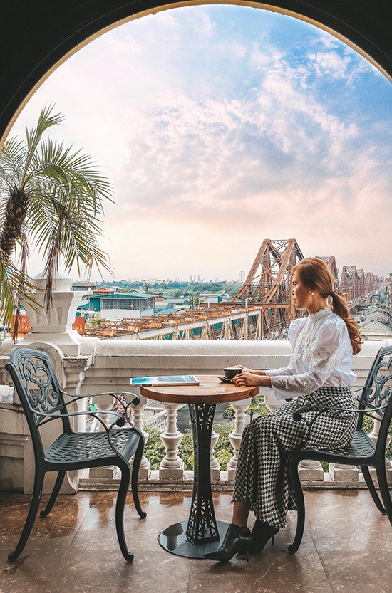 Điểm dừng chân đầu tiên của cô là cầu Long Biên bắc qua sông Hồng. Thay vì đứng trên cầu, Trang chọn quán Serein Cafe & Lounge để có được những khoảnh khắc yên tĩnh ngắm Hà Nội trong nhiều mảng màu đối lập. 