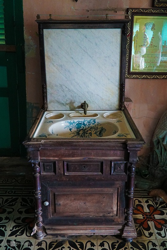 Một chiếc bồn rửa mặt có chân đế bằng gỗ, mặt lavabo hoa văn tinh xảo.