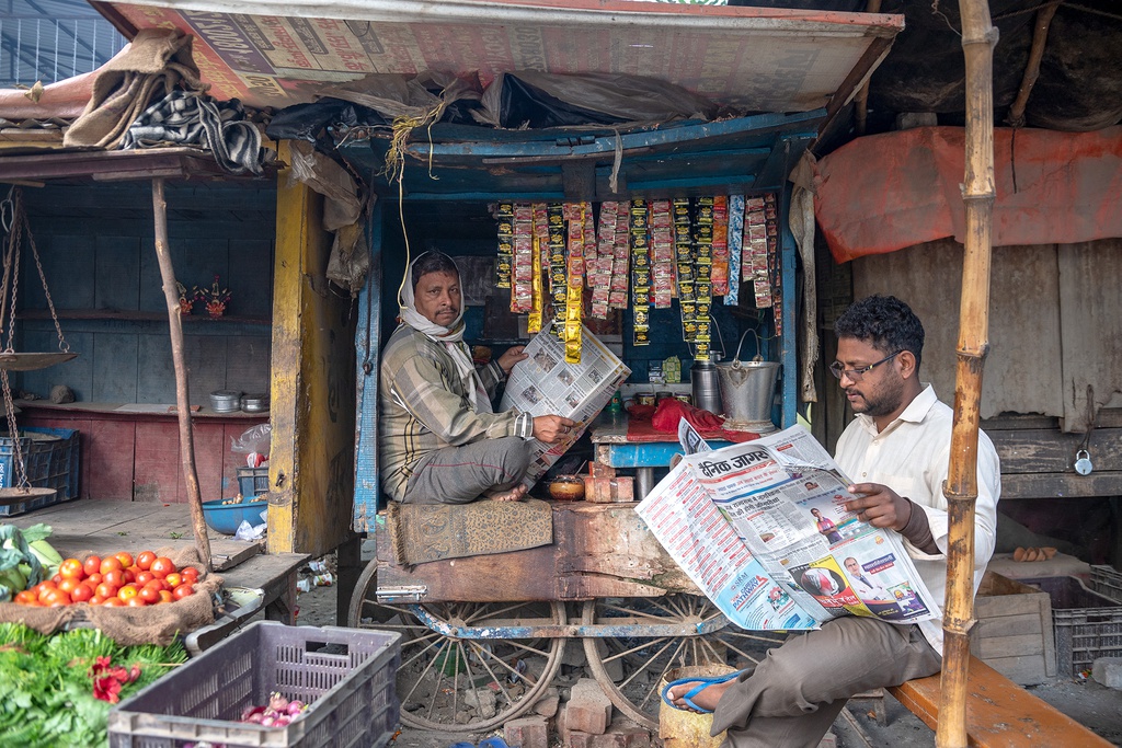 Hai người đàn ông bán hàng đọc báo buổi sáng. Đây cũng là hình ảnh cho thấy cuộc đời nghèo khó của người dân thành phố bên bờ sông linh thiêng này.