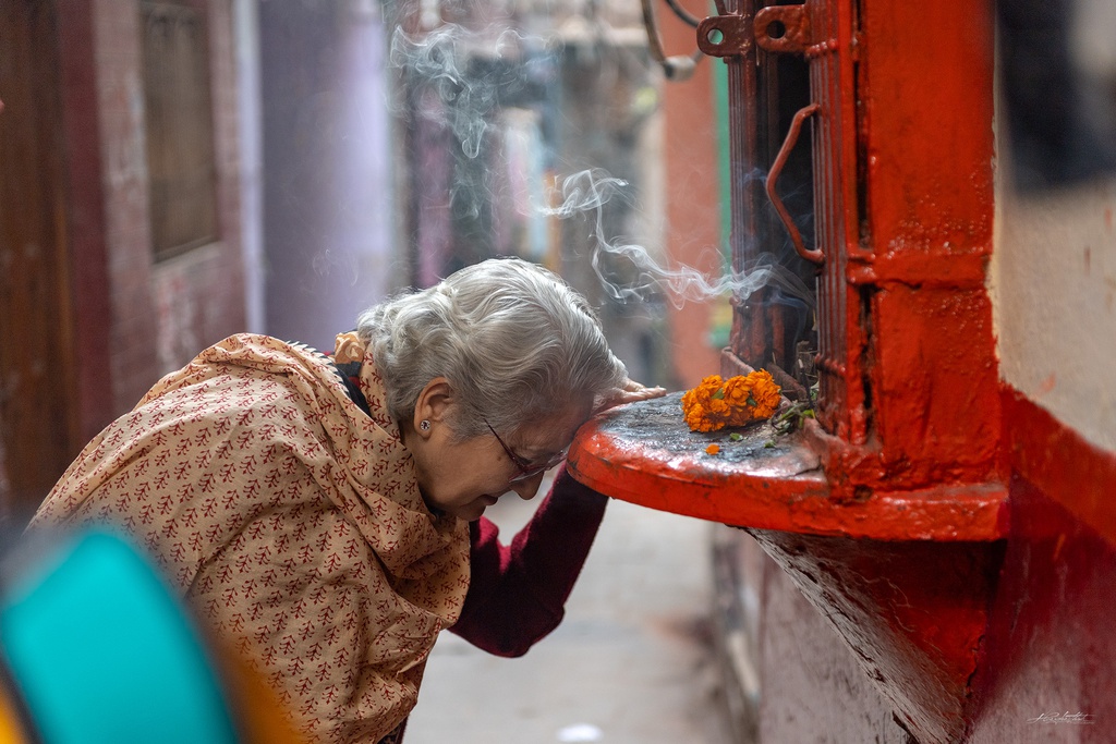 Người phụ nữ cao tuổi Ấn Độ cầu nguyện trong một con ngõ nhỏ vào buổi sáng. Thành phố này là một trong những địa điểm thiêng liêng nhất của đức tin Hindu. Người dân địa phương tin rằng tại đây, linh hồn sẽ được gửi thẳng lên trời, đến nơi ở của những thần linh.