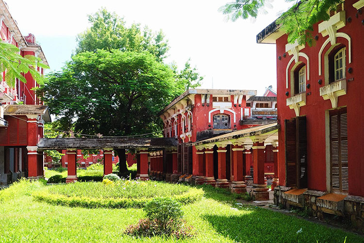 Khoảng đất trống giữa các khu nhà được phủ xanh bởi thảm cỏ và cây cao, tạo không gian dịu mát trong ngôi trường màu đỏ. Ảnh: Nguyễn Hoàng Hà.