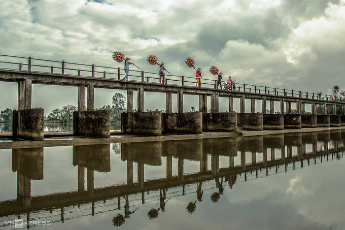 Người dân gánh hoa giấy trên cầu dẫn vào đập La Đập, huyện Phú Vang.