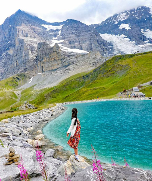 Thay vì lên đỉnh Jungfraujoch với mức giá khá đắt (4,5 triệu đồng/người) và chưa chuẩn bị đủ quần áo lên núi tuyết, Thùy Dương lại tiếp tục để bản thân "lạc" vào khung cảnh cổ tích ở đây. Lần này, cô nàng đến một trong những hồ nước đẹp nhất Kleiner Scheidegg. "Mất tầm 45 phút để đến nơi, trừ việc trời gió tung người và rét cắt da ra thì cảnh hồ nước xanh ngắt bên dưới, xung quanh là hoa tím mọc trên các mỏm đá, ngước mắt lên là thấy ngọn núi sừng sững phủ tuyết trắng quá đủ cho một chuyến đi. Nếu có dự định leo núi chặng này, bạn nên mang giày thể thao và quần áo hợp lý", Dương tư vấn.