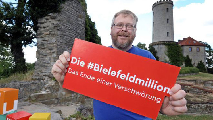 Achim Held giơ biển ủng hộ cuộc thi "Bielefeld không tồn tại". Ảnh: Bielefeld marketing.