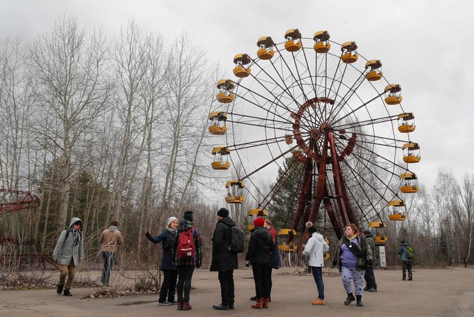 Series phim về thảm họa hạt nhân Chernobyl chiếu trên HBO năm 2019 khiến ngày càng nhiều du khách tìm đến thành phố Pripyat (Ukraine) để khám phá. Trong hình là du khách ở một khu vui chơi bỏ hoang, bên cạnh là chiếc đu quay cũ ở Pripyat.
