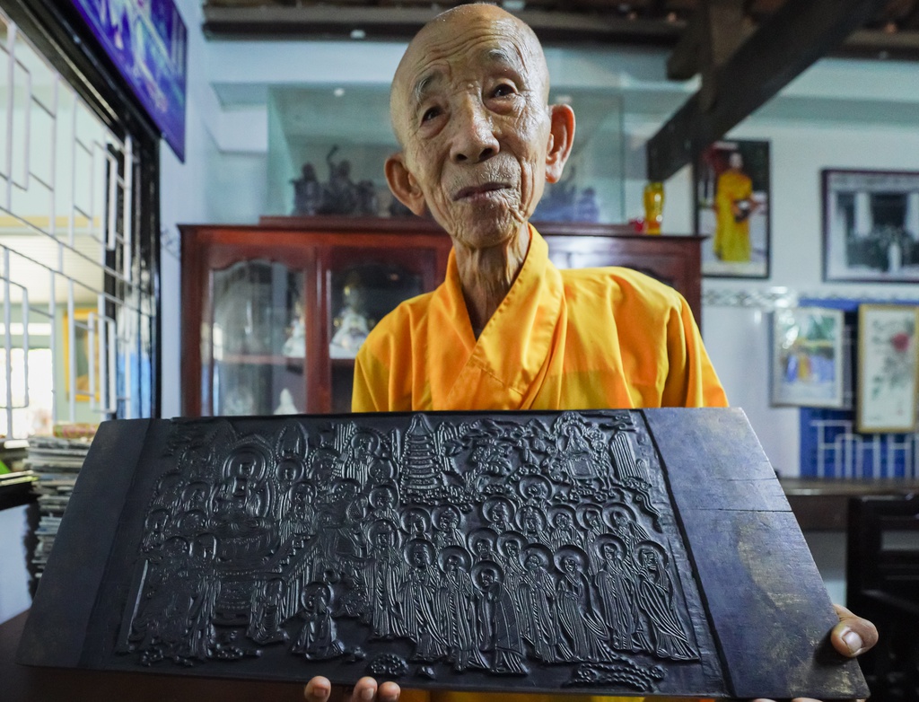 Thầy Thích Huệ Tánh cầm trên tay một tấm mộc bản khắc họa hình ảnh Đức Phật Thích Ca đang thuyết pháp cho thánh chúng nghe. Đây không chỉ là những hình ảnh minh họa của Đức Phật với chúng sinh mà còn là tác phẩm điêu khắc nghệ thuật quý hiếm.